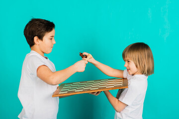 Two serious boy playing chess, studio, blue background