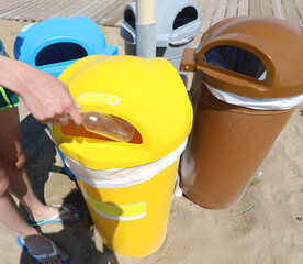 Wall Mural - four bins for separate waste collection on the beach in summer and the person