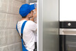 © yaroslav1986 - Uniformed repairman repairs the refrigerator door in the kitchen