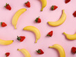 Summer pattern made with bananas and strawberries on pastel pink background. Minimal fruit and vegetable texture concept. Healthy vegetarian food composition with long summer shadows.