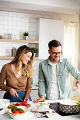 Happy smiling couple cooking together. Boyfriend and girlfriend preparing pasta at home