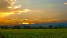 Time Lapse Video 4k, Beautiful Landscape Sunset Over The Rice Paddies Is Growing With Ban Den Sali Sri Muang Gan Temple (Wat Ban Den) In Background Of Chiang Mai, Thailand.