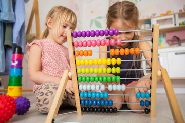 Little children in kindergarten learn to count on abacus, bright wooden toys in the nursery