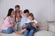 © New Africa - Father reading book to family on sofa in living room