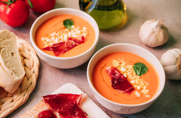 Two bowls of Salmorejo tomato soup with jam, olive oil and boiled egg on marble table. Spanish cold gazpacho puree. High angle view