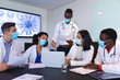 © Wavebreak Media - Team of diverse doctors wearing face mask discussing together over laptop in the meeting room