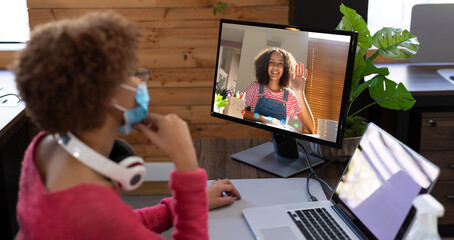 Canvas Print - Businesswoman wearing face mask, sitting at desk using computer having video call