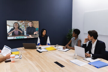 Poster - Diverse group of business colleagues having video call with businesswomen on screen in meeting room