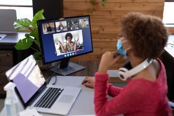 Poster - Businesswoman wearing face mask having video call with coworkers