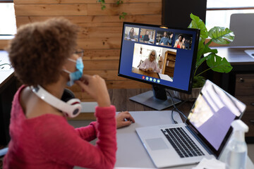 Poster - Businesswoman wearing face mask having video call with coworkers