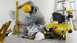 © amedeoemaja - house renovation concept, man worker looks at the spirit level checks the wall, helmet and safety headphones, air compressor and construction tools in background