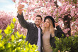 © New Africa - Happy couple taking selfie near blossoming sakura outdoors on spring day