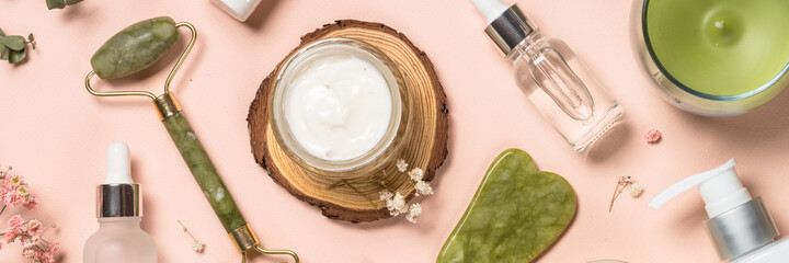 Wall Mural - cosmetic products - jade roller and gua sha massager with cream and serum bottles at pastel backgrou