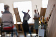 © Wavebreak Media - People working at a painting class in an art studio, a jar of paintbrushes in the foreground