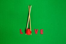 Top View Of Red Yarn Ball Between Food Sticks And Love Title On Green Background