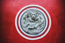 Round Shaped Ornamental Dragon Relief On Red Wall Of Traditional Oriental Temple In Yunnan