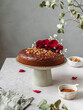 © Cintia Viudez/ADDICTIVE STOCK - Delicious biscuit chocolate cake garnished with flower buds and nuts served on stand on table