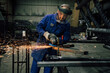 © Ekaitz Gerique/ADDICTIVE STOCK - Workman in protective mask and blue workwear grinding metal part with angle grinder at workbench in professional garage