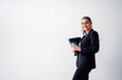 © Jake Jakab/ADDICTIVE STOCK - Positive middle aged female entrepreneur with ponytail wearing formal suit looking at camera while standing with folder and cup of drink on white background