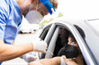 © Jose Carlos Ichiro/ADDICTIVE STOCK - Side view of male doctor in protective uniform, latex gloves and face shield vaccinating African American female patient inside the car on a drive through mobile clinic during coronavirus outbreak