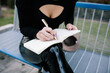 © Joseph Table/ADDICTIVE STOCK - High angle of crop unrecognizable female entrepreneur sitting on bench in city and writing business plan in notebook