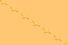 From above of composition of many little yellow airplanes placed against yellow background in studio