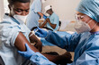 © OIER ASO/ADDICTIVE STOCK - Female doctor in protective uniform and latex gloves vaccinating male African American patient in clinic during coronavirus outbreak