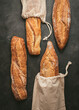 © Olga Vila/ADDICTIVE STOCK - Top view composition of delicious crispy artisan sourdough bread loaves packed in burlap bags on black background