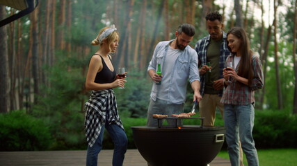 Smiling guys drinking alcohol drinks outside. Friends relaxing near bbq grill