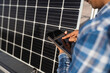 © Ruben Soto/ADDICTIVE STOCK - Cropped unrecognizable ethnic male technician in checkered shirt browsing tablet while standing near photovoltaic panel located in modern solar power farm