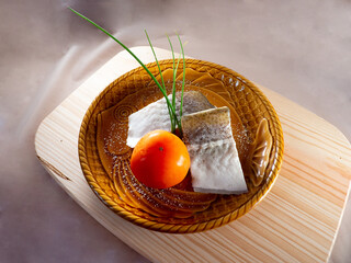 Wall Mural - High angle shot of slightly salted raw fish fillets with green onion and tomato on a plate