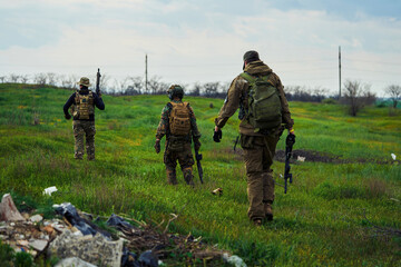 Wall Mural - Soldiers with weapons in their hands are walking across the field