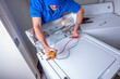 © spatesphoto - Appliance repairman in uniform fixing a washing machine