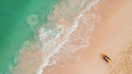 Wall Mural - Aerial view of a woman laying on the beach sand. Girl in bikini relaxing and watching the waves