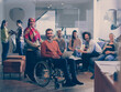 © .shock - Disabled businessman in a wheelchair at work in modern open space coworking office with team