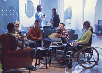 Handicapperd businesswoman in a wheelchair on meeting with her diverse business team brainstorming at office