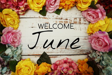 Wall Mural - welcome june text and flowers colorful border frame on wooden background