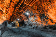 Tunnel Of The Mining Of An Underground Mine. Lots Of Pipelines On The Ceiling And Rail Track For Trolleys