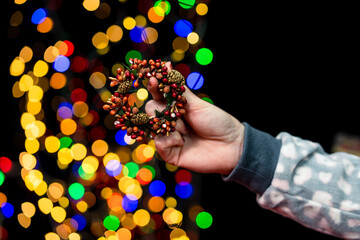 Sticker - Closeup shot of a female hand holding Christmas decoration with bokeh lights effect