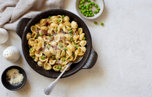 Pasta With Fried Bacon, Green Peas And Parmesan Cheese In Rustic Cooking Pan