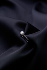 Diamond ring on black silk background with copy space