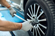 © Drazen - Close-up of repairman changing tire at car service workshop.