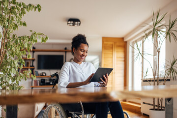 Smiling black woman using digital tablet at home.