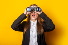Surprised Young Business Woman Looking Through Binoculars On Yellow Background