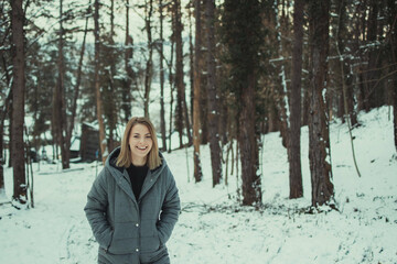 Sticker - Shallow focus shot of a blonde short-haired girl wearing a winter jacket in a snowy forest