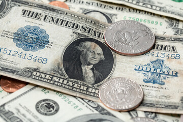 US dollar from 1923 next to half dollar coins. Dollar background. US currency evolving over time, large one dollar banknote on top of new dollar bills