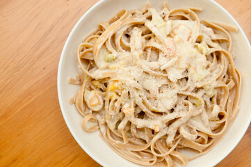 Poster - Top view of delicious pasta with cheese on a white plate isolated on a wooden surface