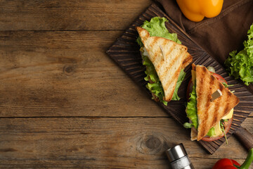 Wooden board with tasty sandwiches on table, flat lay. Space for text