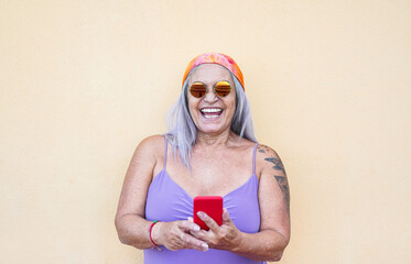 Crazy old hippie woman with smartphone - Cool senior person with tattoo