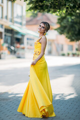 Canvas Print - Vertical portrait of a gorgeous Caucasian blonde female spinning her elegant yellow dress in street